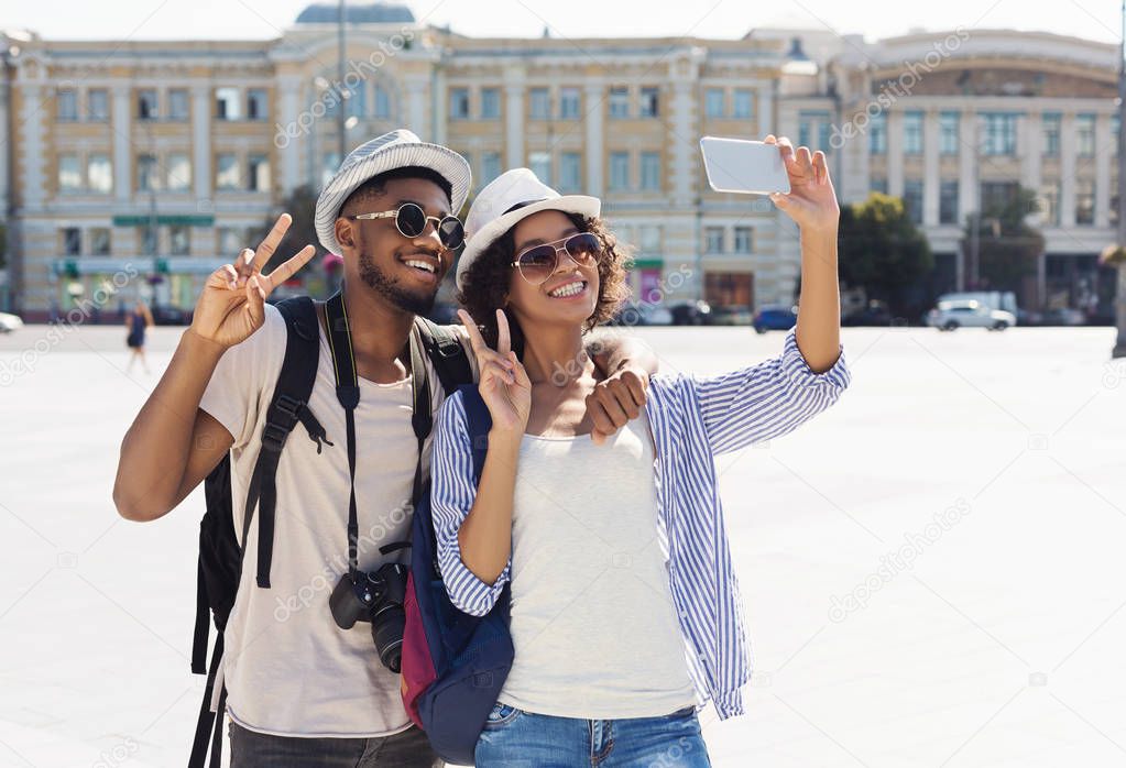 Happy african-american tourists taking selfie in new city