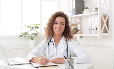 Ofiste oturan ve yazma gülümseyen çocuk doktoru