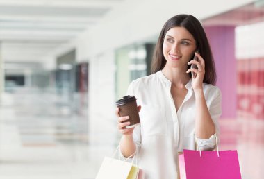 Cep telefonu üzerinde konuşurken ve alışveriş merkezinde kahve içme kadın