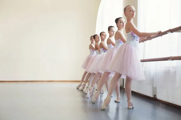 Молодые балерины репетируют в балетном классе, выполняют различные упражнения — стоковое фото