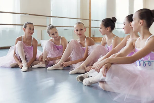 Piccole ballerine che parlano in studio di danza classica, sedute sul pavimento — Foto Stock