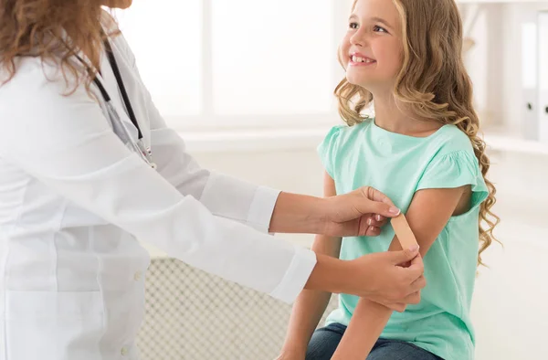 Kinderarzt klebt Mädchen Pflaster auf den Arm — Stockfoto