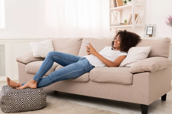 Glad afroamerikansk flicka messaging på smartphone hemma — Stockfoto
