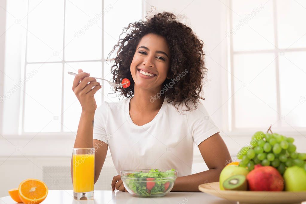 African-american woman with vegetable salad and fresh juice