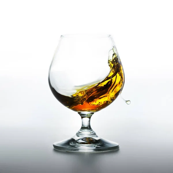 Cognac glass with splashing brandy inside — Stock Photo, Image