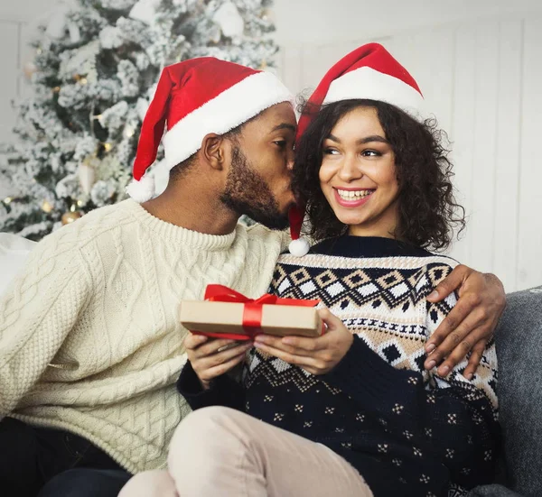 Young man giving her girlfriend present and kissing cheek