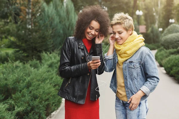 Happy female friends listen to music outdoors — Stock Photo, Image