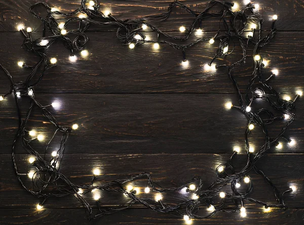 Frame of christmas garland lights on wooden background — Stock Photo, Image