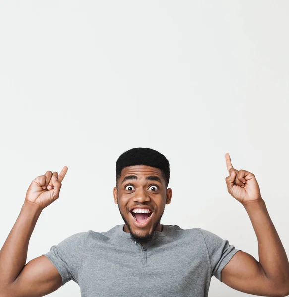 Homem afro-americano entusiasmado apontando para cima no espaço de cópia — Fotografia de Stock