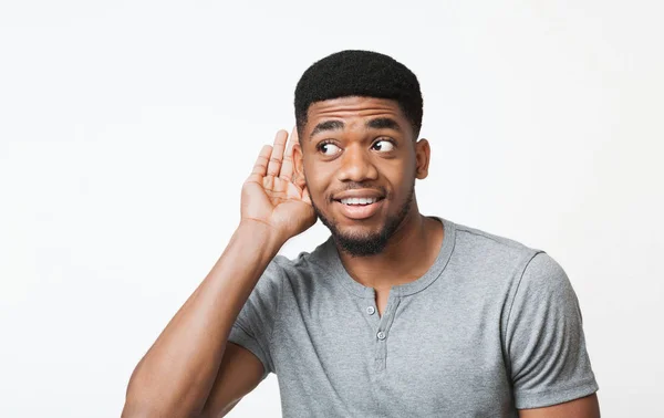 Zvědavý afroameričan držící se za ruku u ucha — Stock fotografie