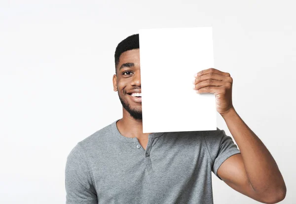 Homem afro-americano cobrindo metade de seu rosto com papel limpo — Fotografia de Stock