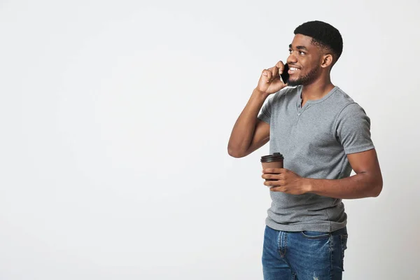 Africano-americano homem segurando café e falando no smartphone — Fotografia de Stock