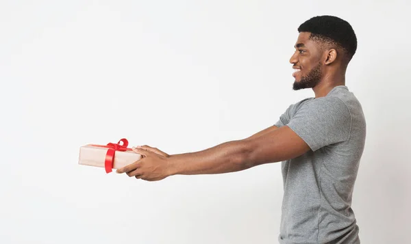 Uomo nero in possesso di regalo in scatola bianca avvolto con nastro rosso e fiocco — Foto Stock