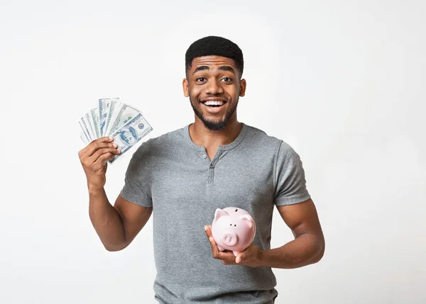 Preto homem segurando dinheiro e piggybank no branco fundo — Fotografia de Stock