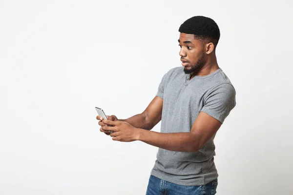 Homem afro-americano decepcionado usando smartphone em branco — Fotografia de Stock