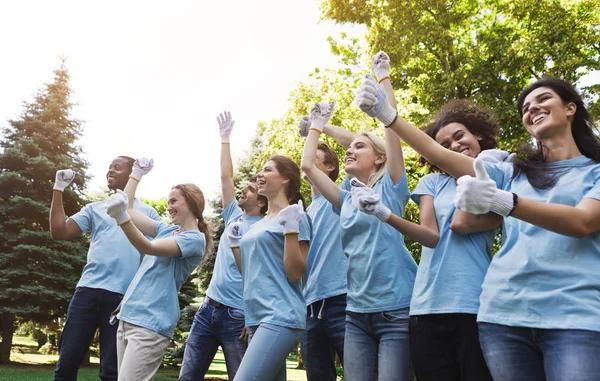 Gruppo di volontari felici che festeggiano il successo nel parco — Foto Stock