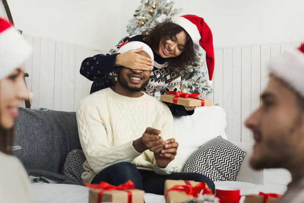 Christmas holiday couple happy young woman surprise boyfriend,covering mans eyes, isolated over white background wear red new year hats and shirts