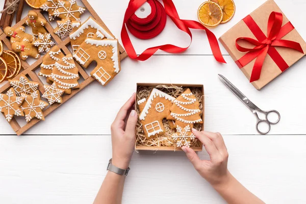 Vrouw verpakking kerstkoekjes peperkoek in geschenkdoos — Stockfoto