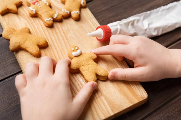 Kind versieren zelfgemaakte peperkoek cookies op houten plank — Stockfoto