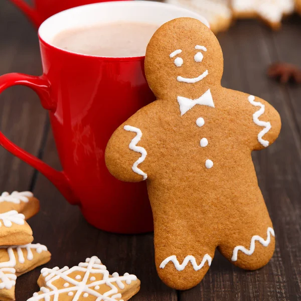 Lebkuchenmann lehnt an roter Tasse mit Kakao — Stockfoto