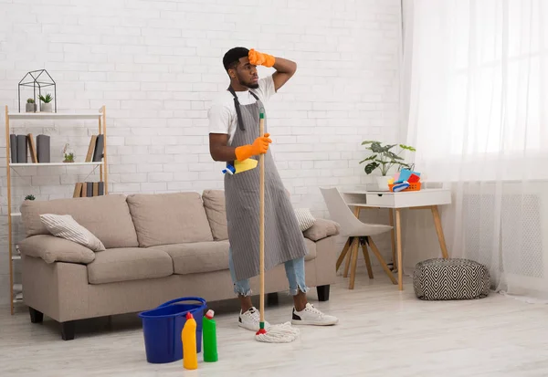 Young tired man cleaning home floor with mop — Stock Photo, Image
