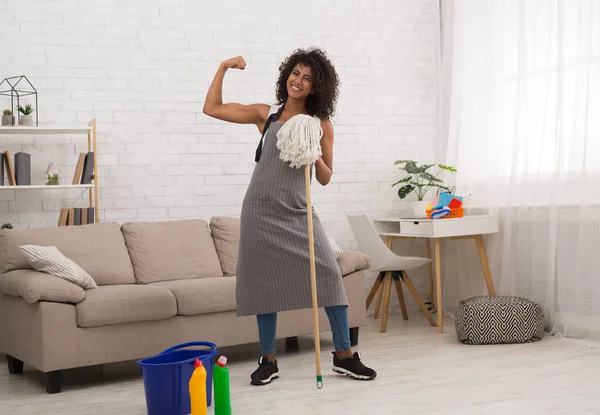 Powerful housewife holding mop and showing biceps — Stock Photo, Image
