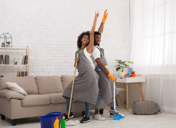 Young couple cleaning home, having fun with mop and broom — Stock Photo, Image
