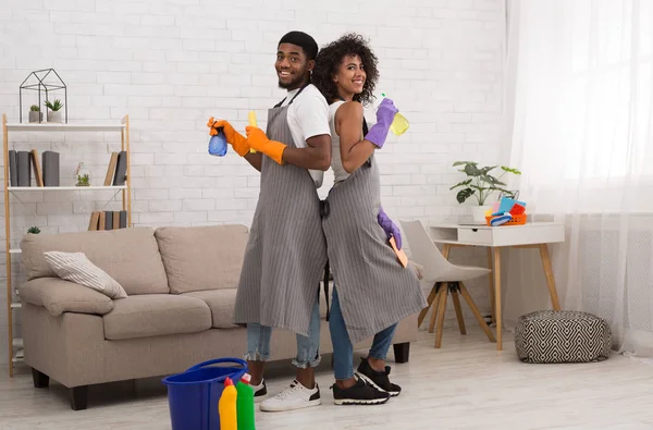 Feliz casal preto segurando detergentes durante a limpeza em casa — Fotografia de Stock