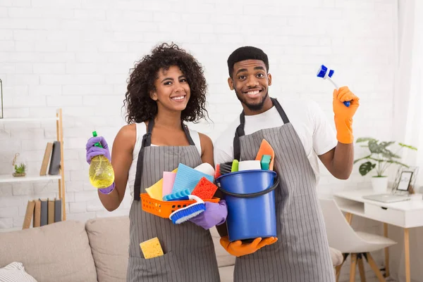 African-american couple holding cleaning tools and detergents — Stock Photo, Image
