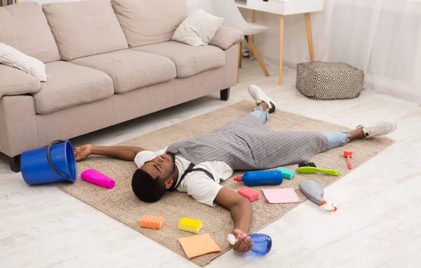 Moe man liggen op tapijt omgeven door schoonmaakproducten — Stockfoto
