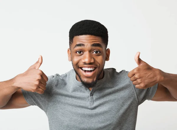 Feliz preto homem mostrando polegares até no estúdio — Fotografia de Stock
