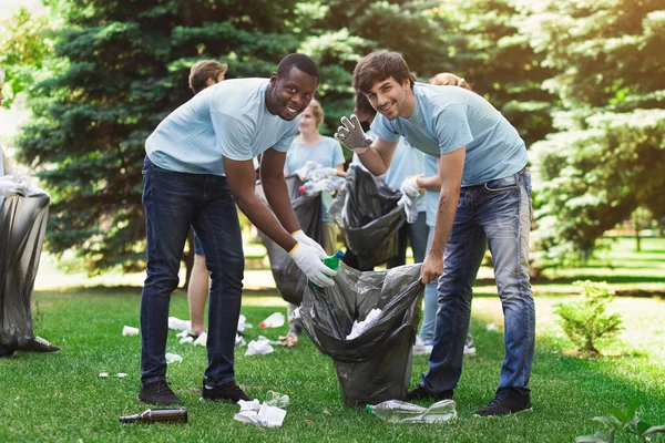 Csoport az önkéntesek, a szemetet táskák tisztító park — Stock Fotó