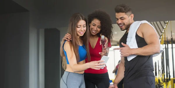 Giovani amici in abbigliamento sportivo si rilassano dopo l'allenamento con lo smartphone — Foto Stock