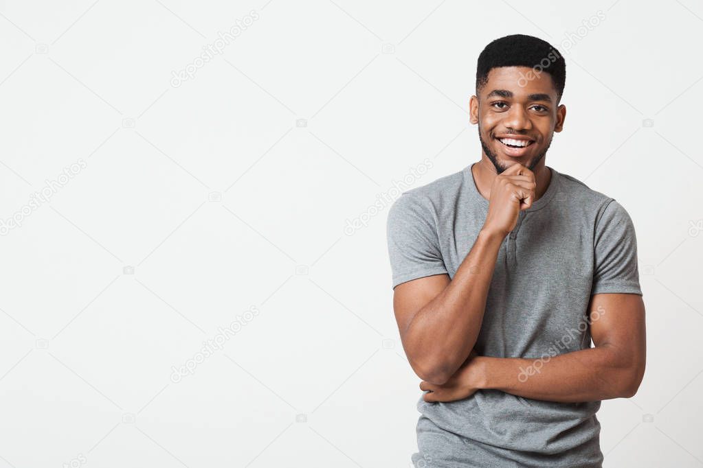 Interested smiling african-american man touching chin, copy space