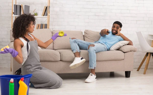 Mujer limpiando casa mientras su novio descansa en el sofá — Foto de Stock