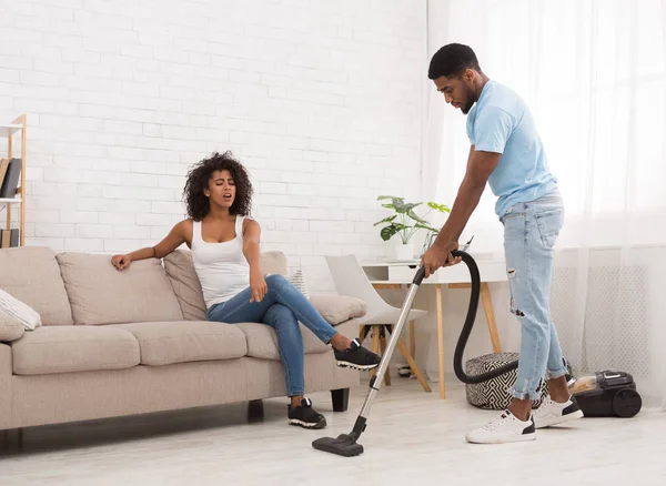Woman relaxing while black man cleaning apartment — Stock Photo, Image