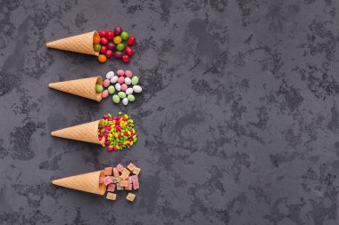 Gözleme külah ile gri arka plan üzerinde renkli parlak şekerler. Düz yatıyordu, en iyi görünümü