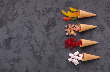 Gözleme külah ile gri arka plan üzerinde renkli parlak şekerler. Düz yatıyordu, en iyi görünümü