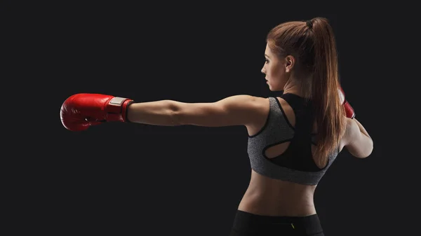 Side view of a gorgeous young woman with boxing gloves