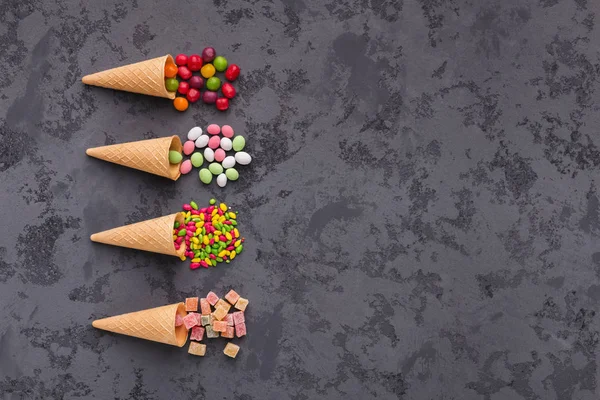 Gözleme külah ile gri arka plan üzerinde renkli parlak şekerler. Düz yatıyordu, en iyi görünümü