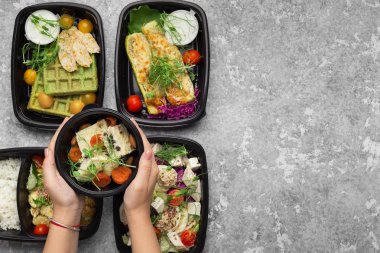 Gri zemin üzerine lezzetli yemekleri ile plastik kaplar