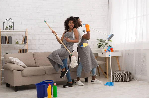 年轻夫妇打扫回家, 有拖把和扫帚的乐趣 — 图库照片