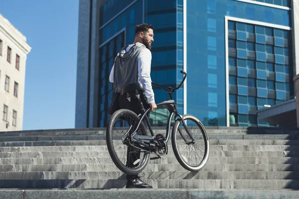 Homem de negócios barbudo carregando sua bicicleta nas escadas — Fotografia de Stock