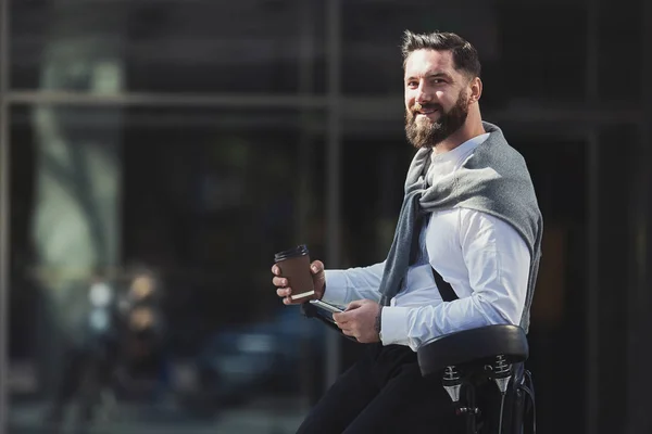 Ung affärsman holding kopp kaffe medan lutande på sin cykel — Stockfoto