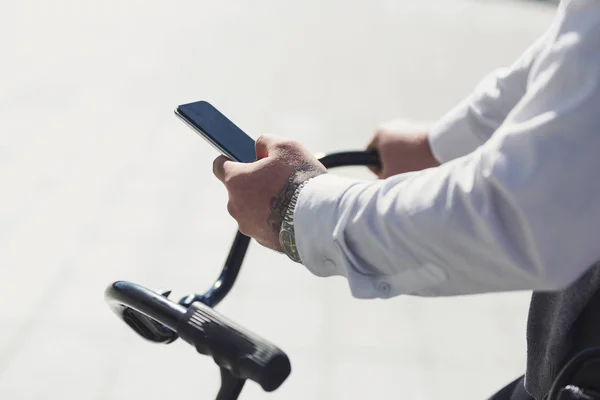 Empresario sosteniendo teléfono móvil mientras se inclina en su bicicleta — Foto de Stock
