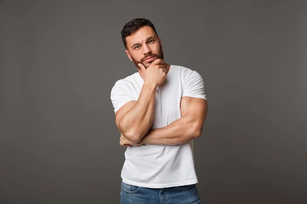 Hombre concentrado con camiseta blanca tocándose la barbilla —  Fotos de Stock