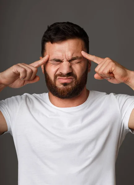 Hombre concentrado sosteniendo los dedos en las sienes de cerca — Foto de Stock