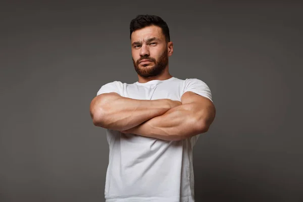 Suspicious young man with crossed big muscular arms — Stock Photo, Image