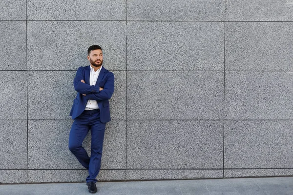 Hombre de negocios guapo posando cerca de la pared gris en el fondo de la calle — Foto de Stock