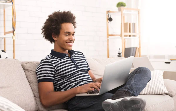 Escribiendo nuevo post de blog. Adolescente afroamericano usando laptop en casa —  Fotos de Stock